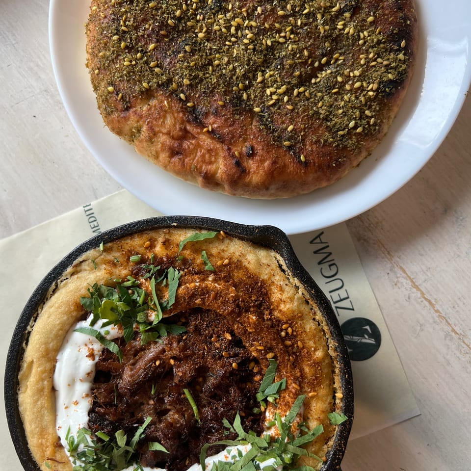 Middle Eastern-style dishes, including za’atar and pine nut-topped flatbread and a skillet dish with meat, yogurt, and herbs.