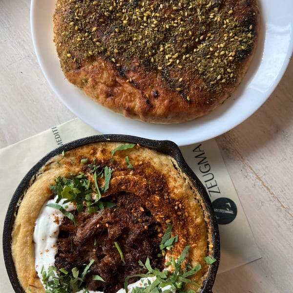 Middle Eastern dishes featuring za’atar-and-pine-nut flatbread and a skillet-topped dish with meat, yogurt, herbs, and spices.